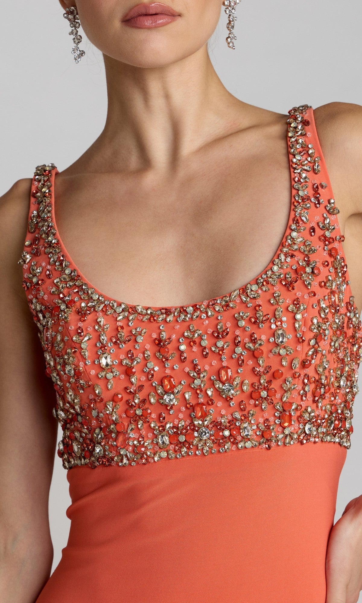 Wearing the Mac Duggal 2253 long formal dress, this woman showcases an orange sleeveless gown featuring a scoop neckline and a crystal-embellished, beaded bodice—an ideal choice for evening occasions.